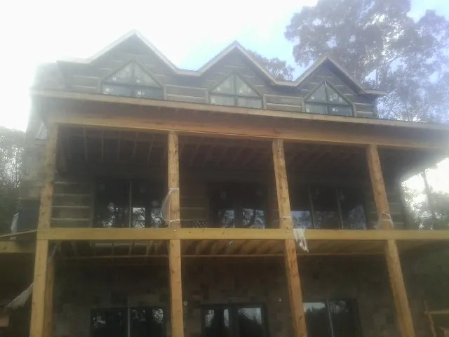 Dormers and porch framing on a large log home under construction — Roof Coating work by our crew in Adamsville