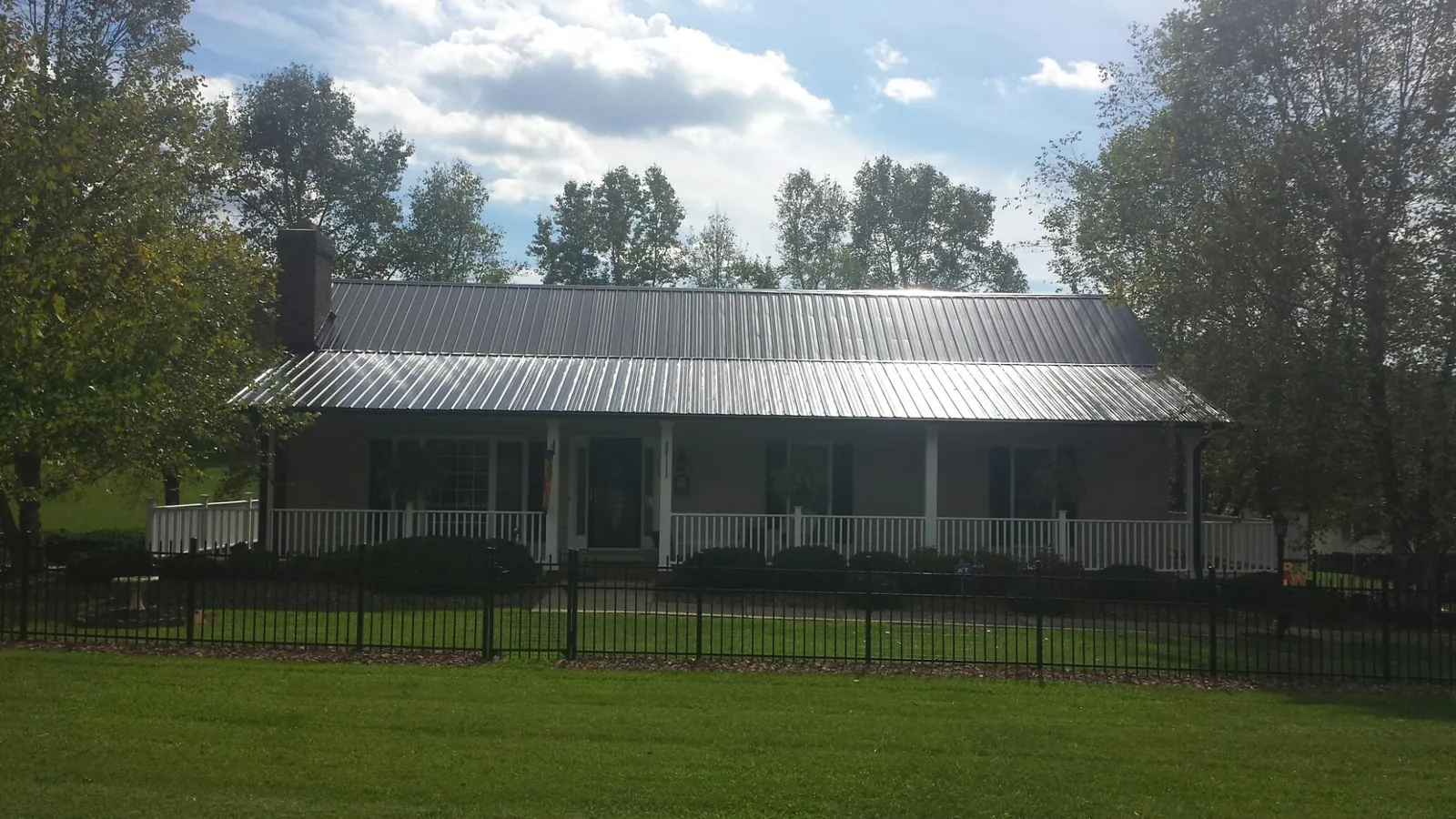 Gray metal roof on a brick ranch with a full width front porch — Gutter Guard Installation work by our crew in Adamsville