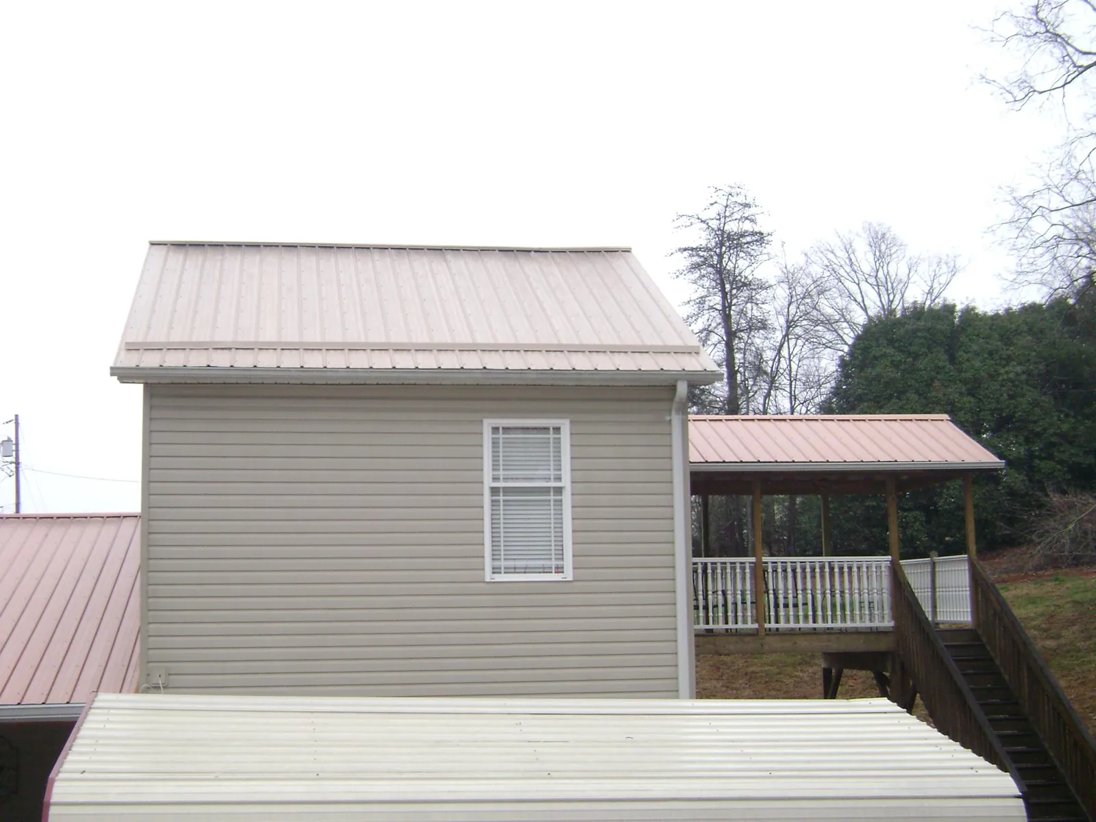 Tan metal roofs on a two story addition and attached porch, from a Roof Replacement job in Adamsville